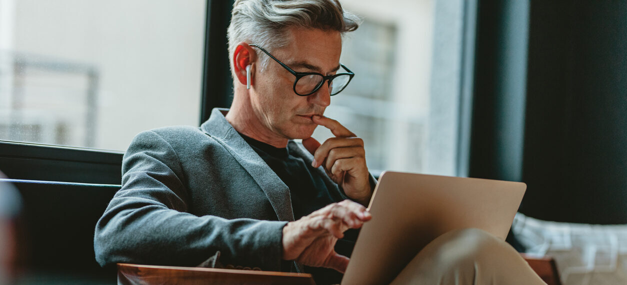 A businessman looking at laptop and thinking.