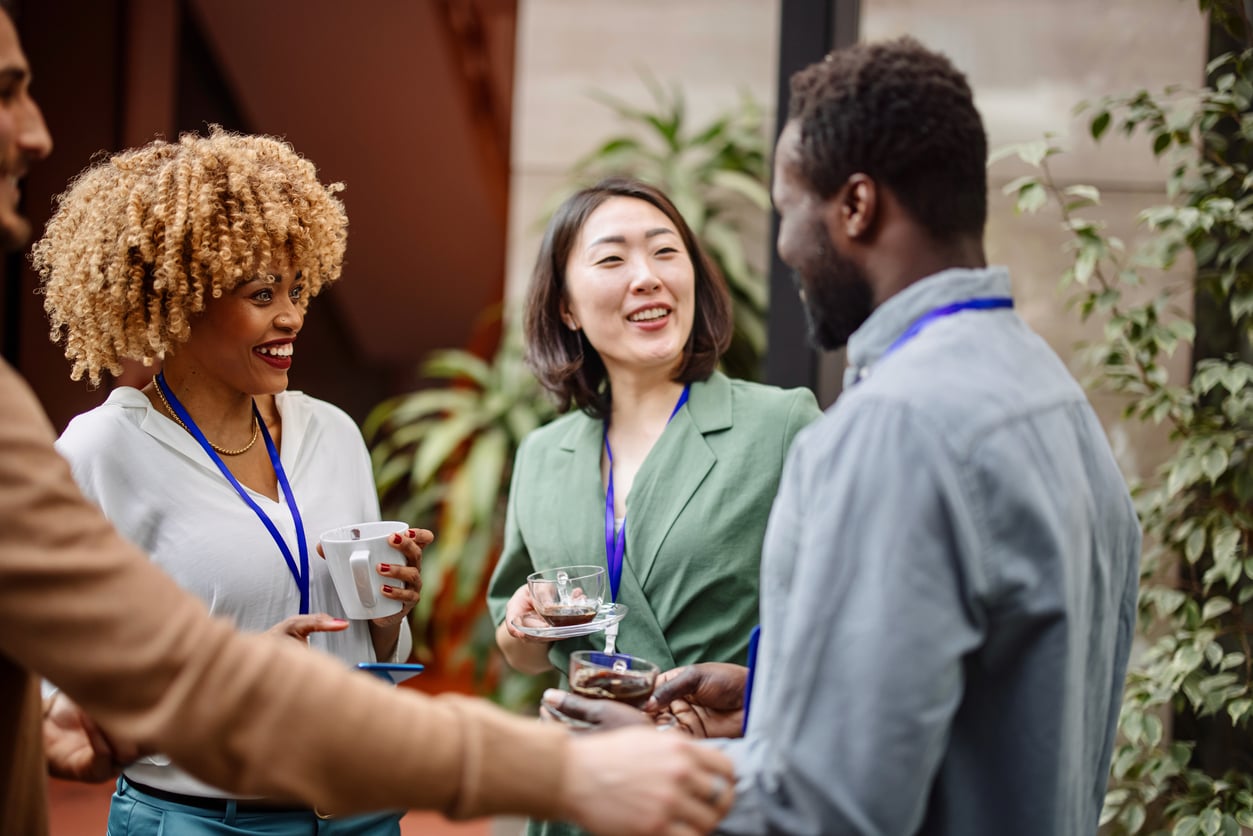 Three business people talking at a convention or work event.