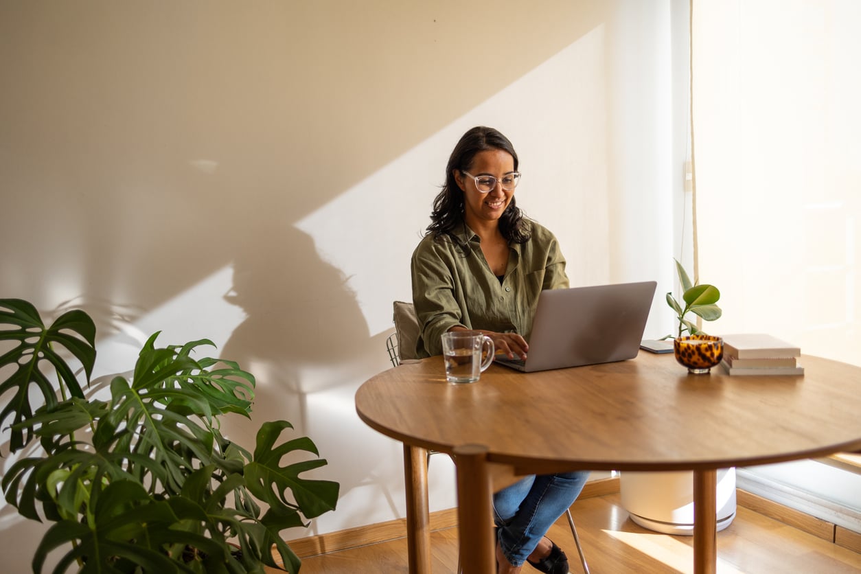 A woman working at laptop on table at home.