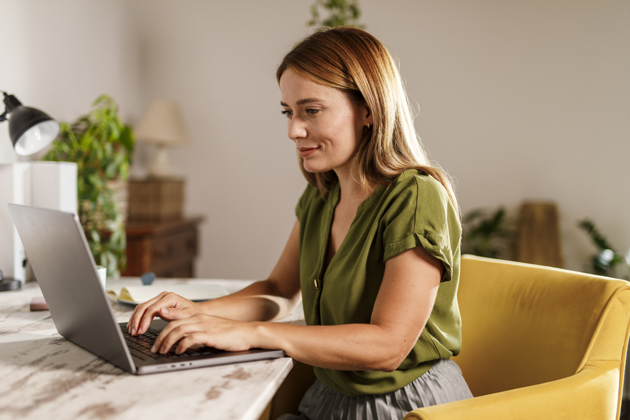 A woman working at a laptop in a home office.