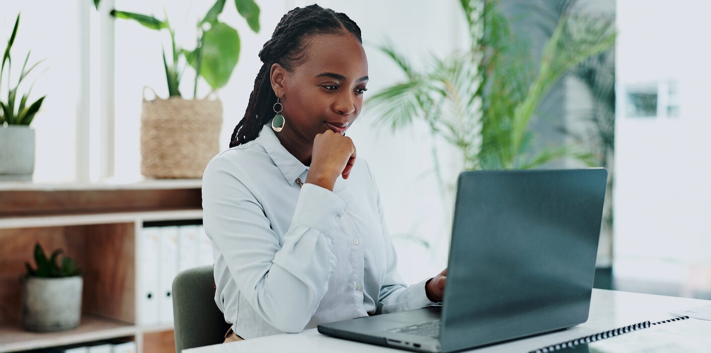 A woman working on laptop at her desk in an office.