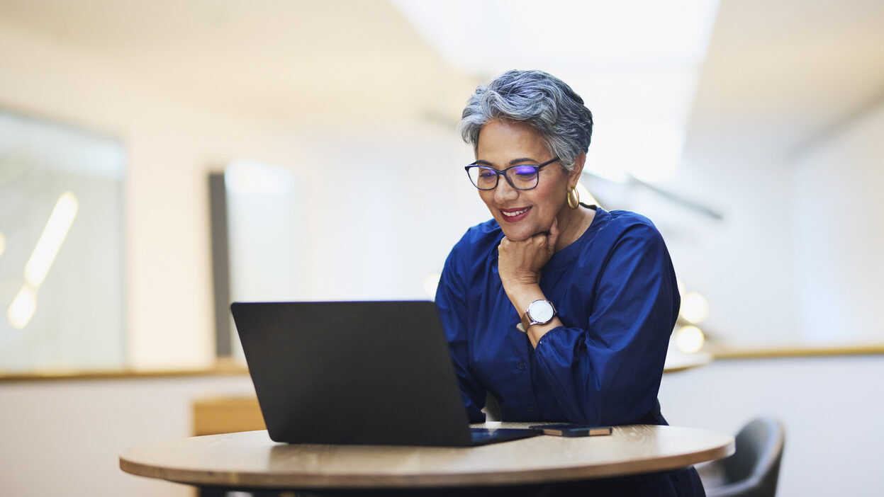A woman working on a laptop at a desk in an office.