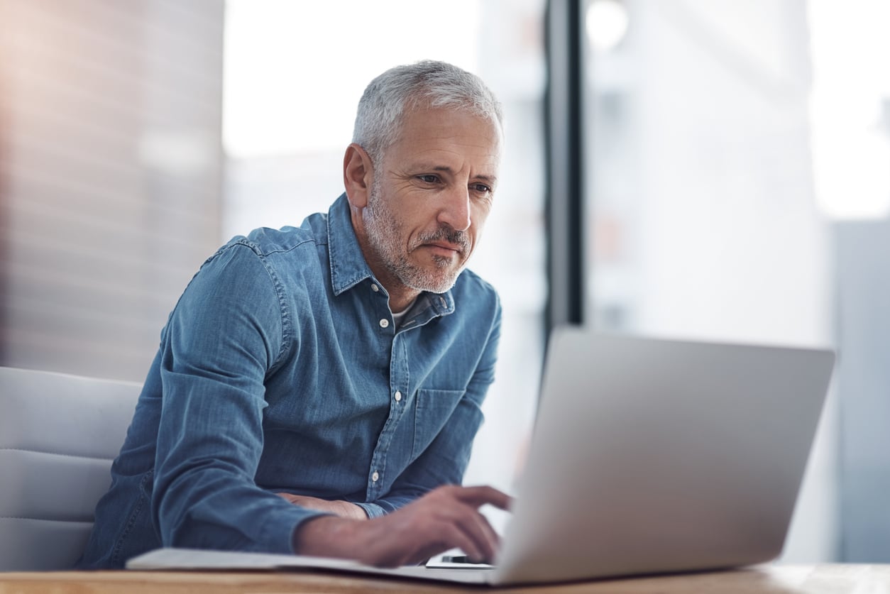 A man sits working at a laptop in an office.